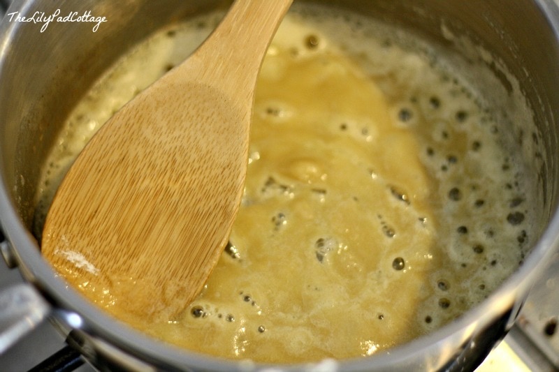 A close up of a metal pan filled with soup and a spoon, with Cheese and Spinach