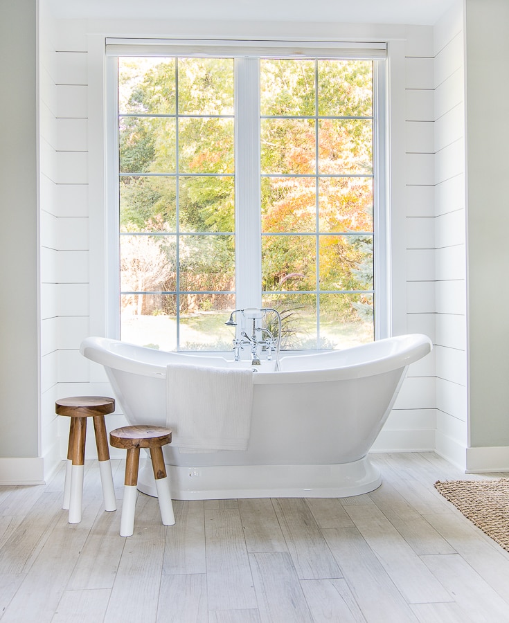 white and blue coastal master bathroom free standing tub and wood stools