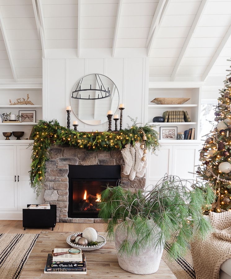 A fire place sitting in a living room filled with furniture and a Christmas tree