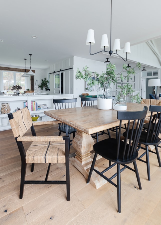 lake house dining room with white walls wood table and black woven chairs 