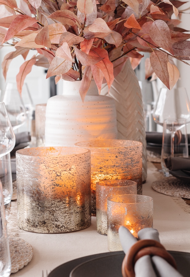 Thanksgiving table decor. White vase with red faux leaves and metallic candle holders