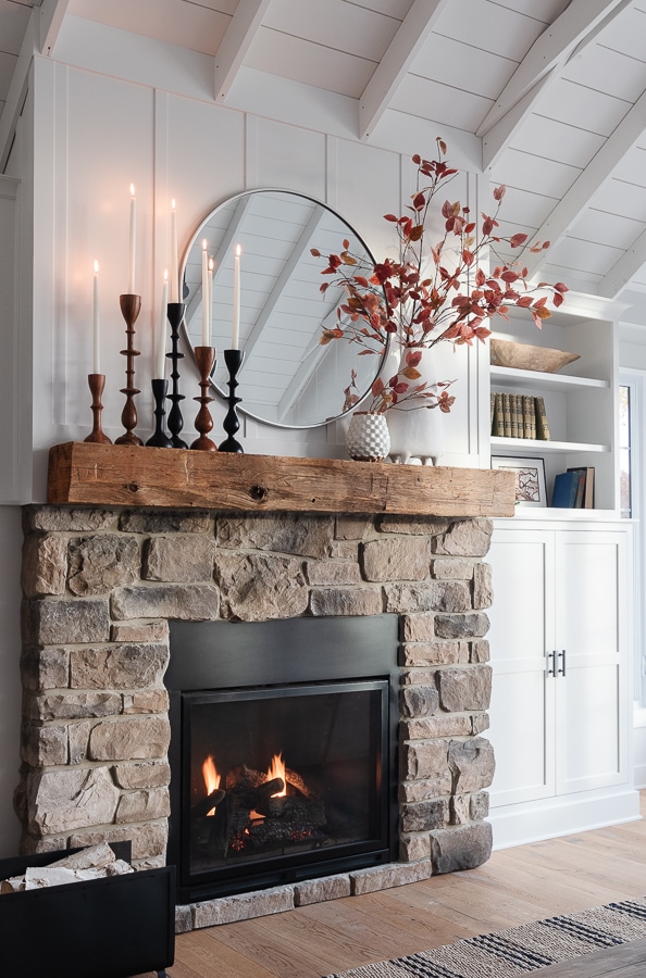 stone fireplace with rustic mantel and white vase and candles.