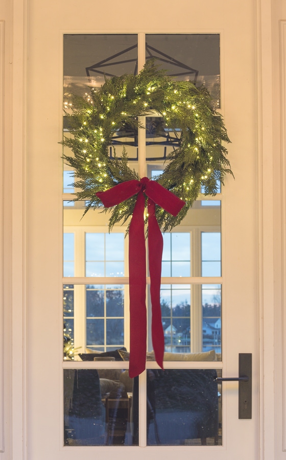 pre-lit christmas wreath with red bow on front door