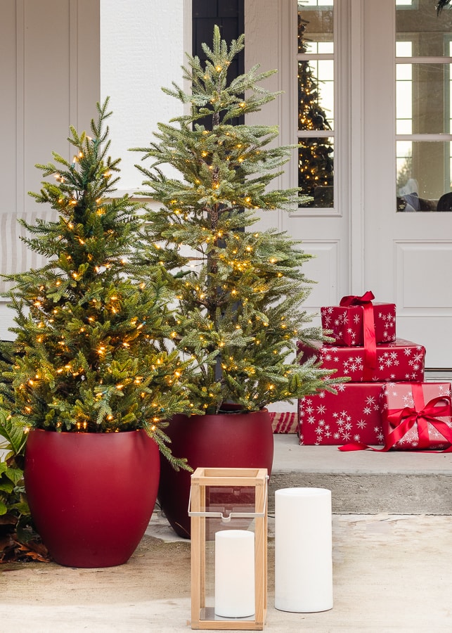 Red planters with mini Christmas trees on front porch