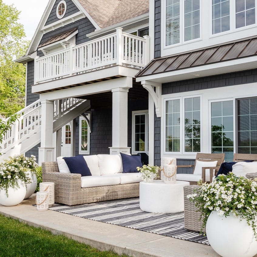 Outdoor furniture on a patio in front of a lake home