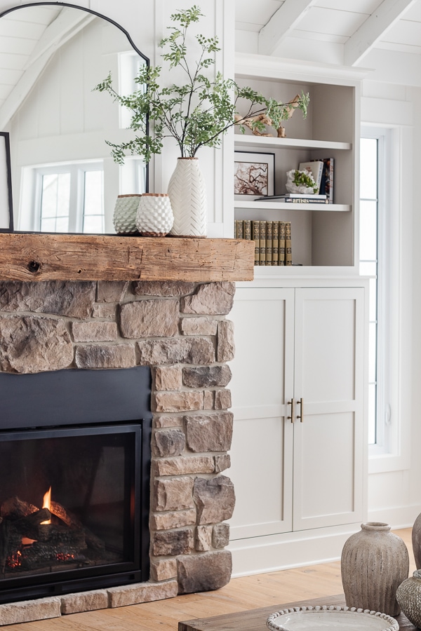 Gray cabinets with stone fireplace and rustic beam