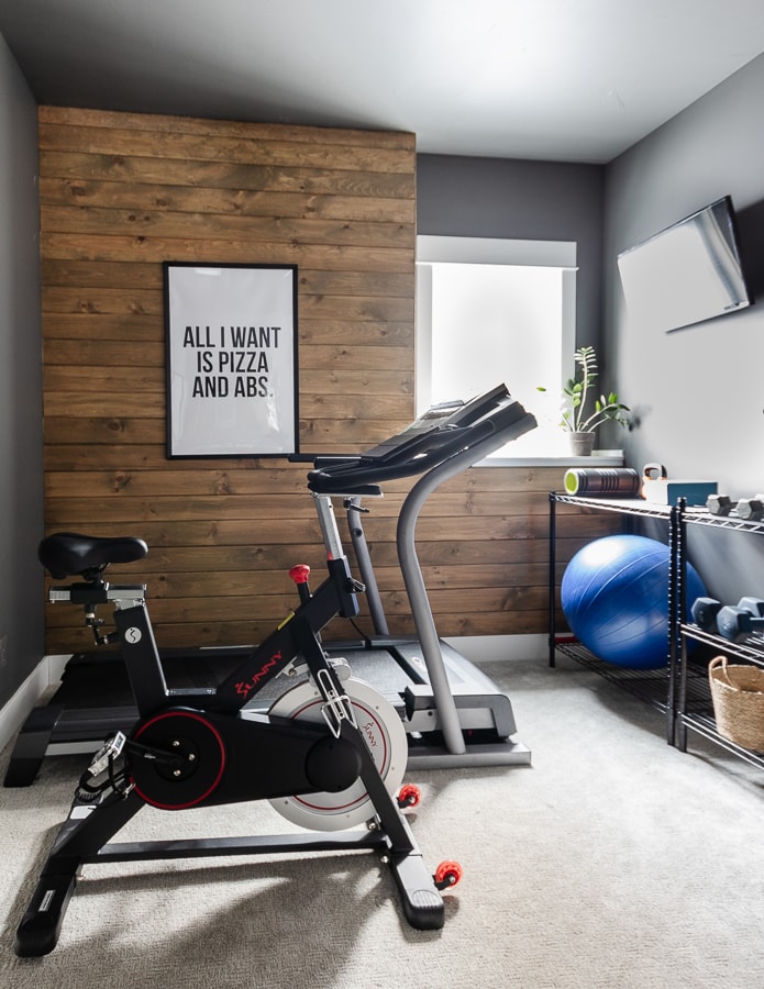 Home gym with stained wood walls, charcoal paint, and exercise equipment