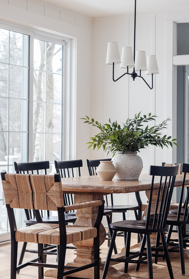 wood dining table with black chairs and plant centerpiece