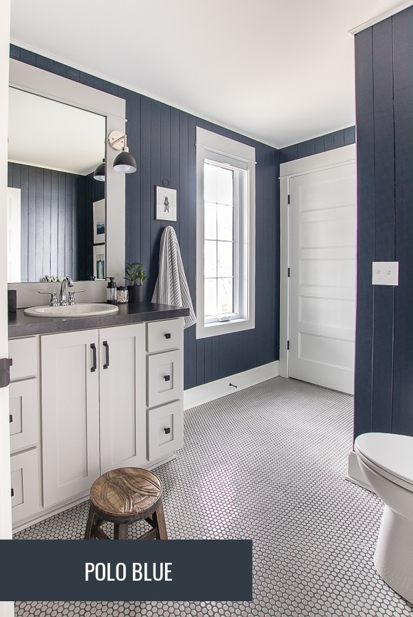 Small bathroom with blue paneled walls and gray penny tile flooring