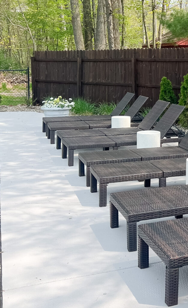 light gray stained concrete pool deck with lounge chairs