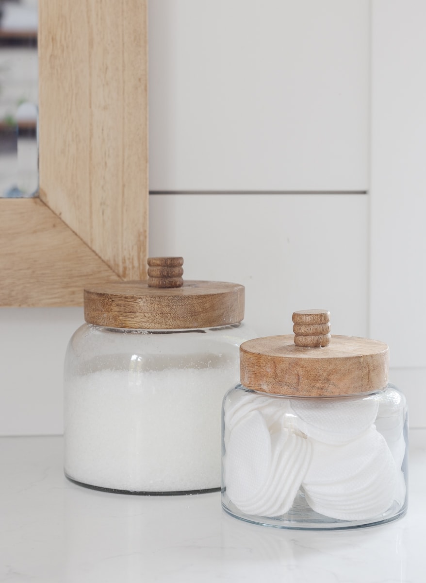 glass jars with wood tops sitting on bathroom counter