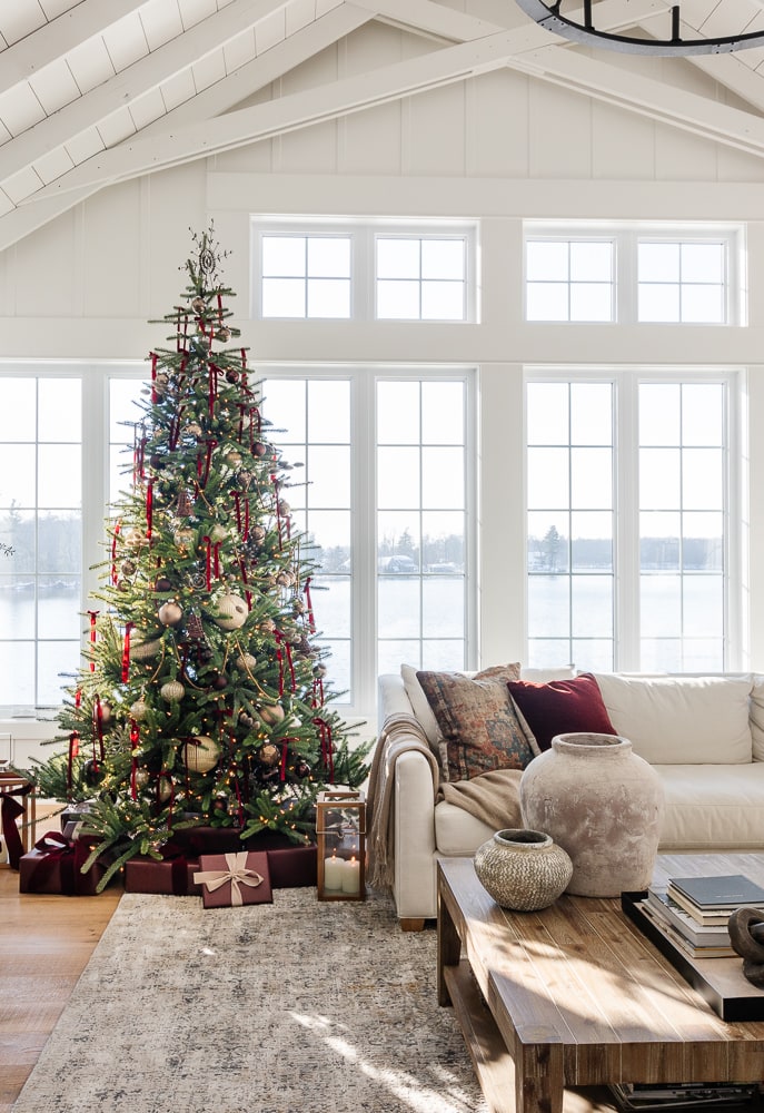 white living room with large windows over looking the lake with burgundy and gold Christmas decor