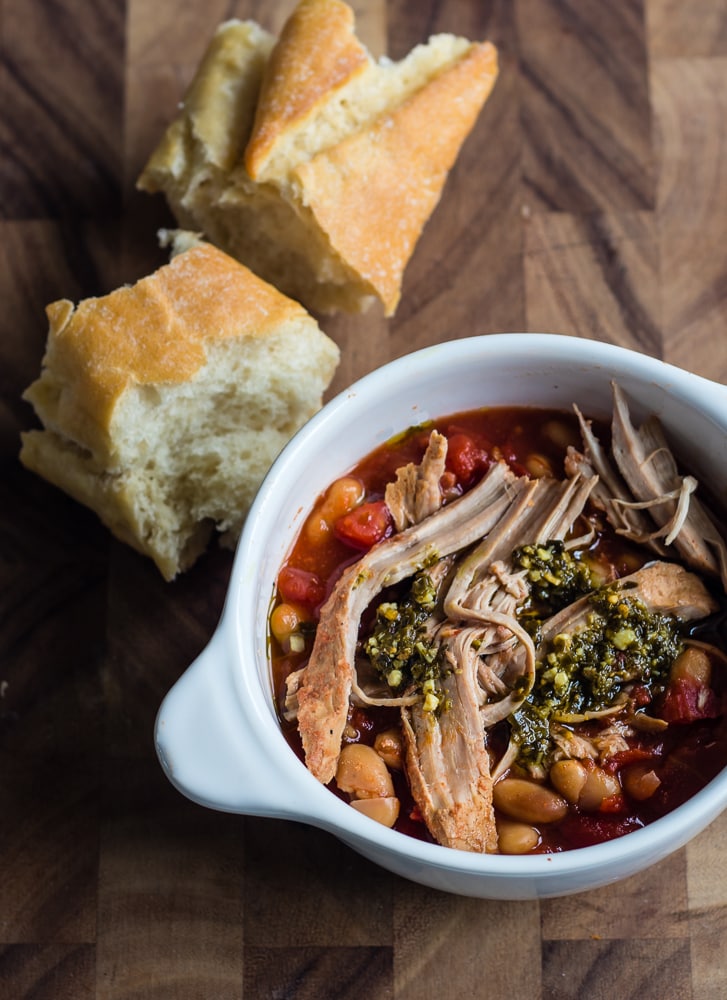 White bowl with pork and beans and tomatoes with crusty bread