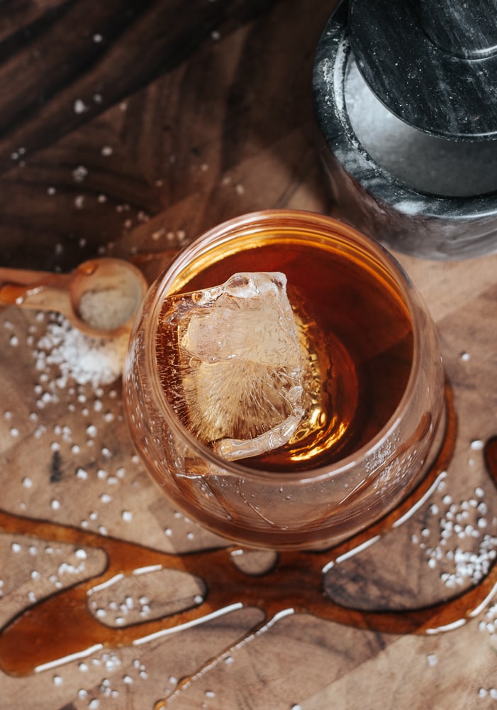 Cocktail glass with bourbon on wood cutting board