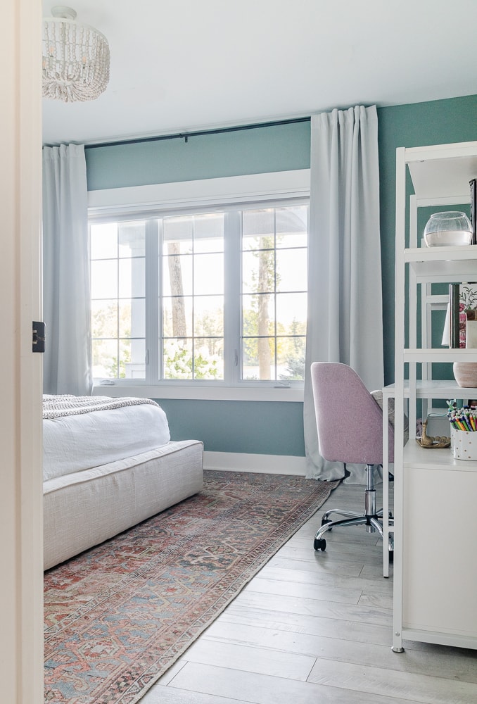 bedroom with teal green walls and white desk and shelves