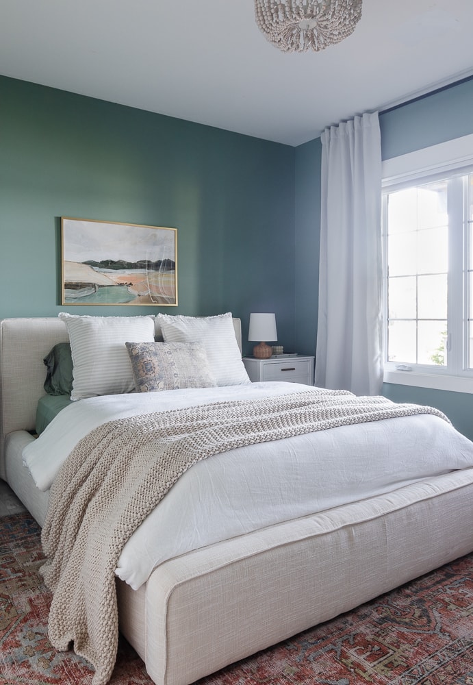 Bedroom with teal walls, upholstered bed, and drapes