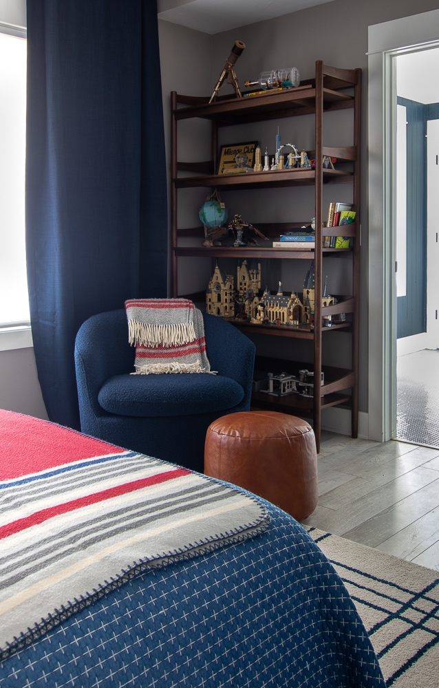 boys bedroom with walnut bookcase and navy armchair 