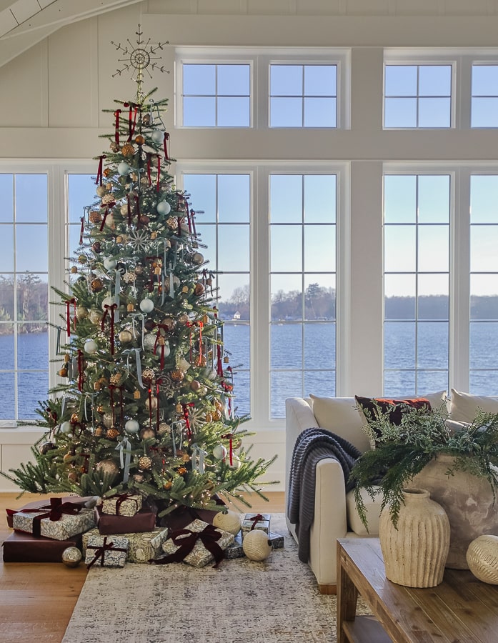 lake house decorated for Christmas with large tree and windows