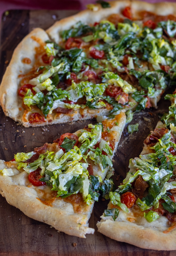 wood cutting board with pizza with bacon lettuce and tomato