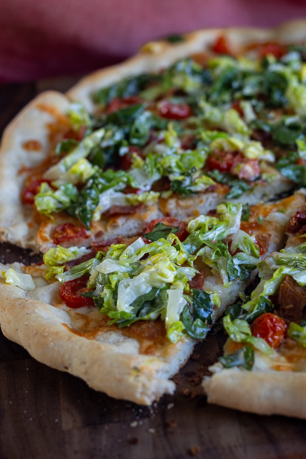 wood cutting board with pizza with bacon lettuce and tomato
