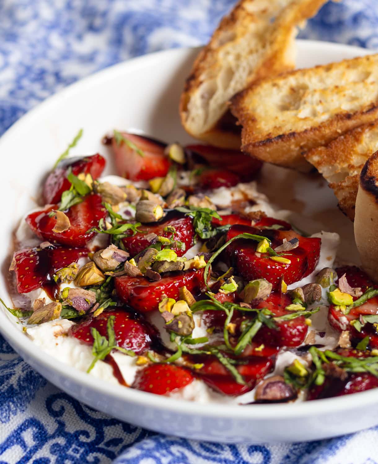 bowl of burrata with strawberries and basil with toasted bread