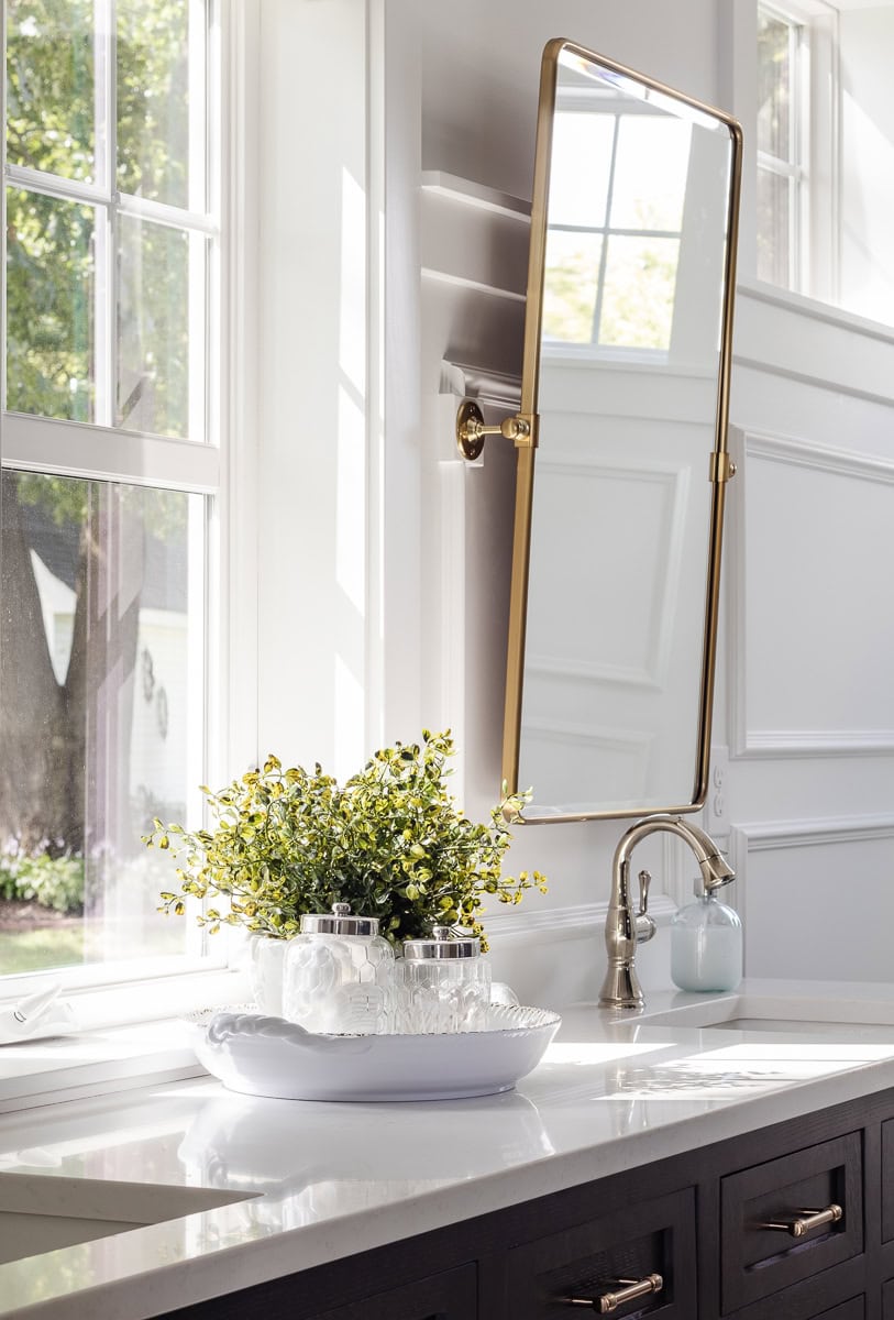 white bathroom corners with brass mirror and chrome faucet