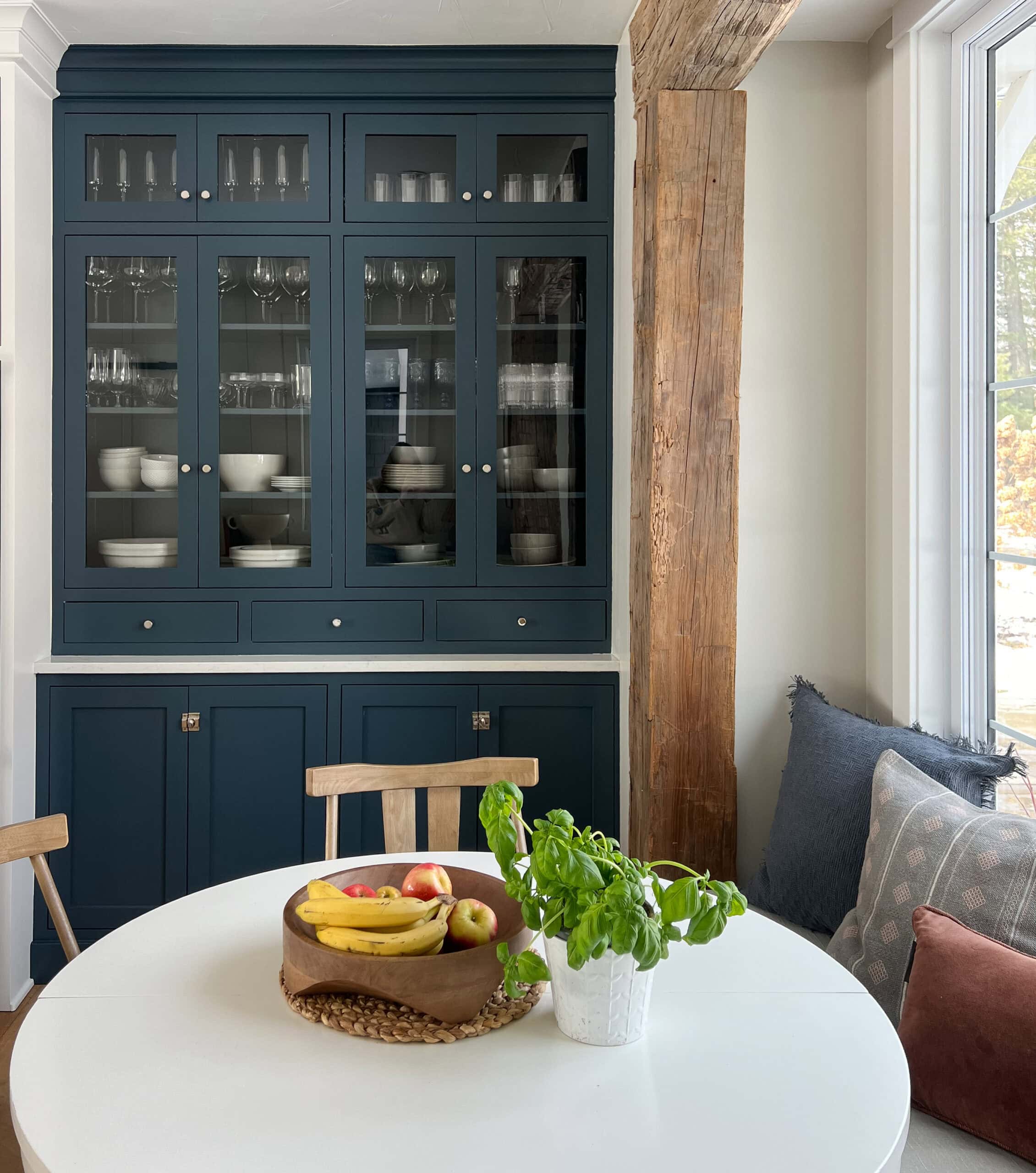 navy cabinets with breakfast nook with rustic beams and white table